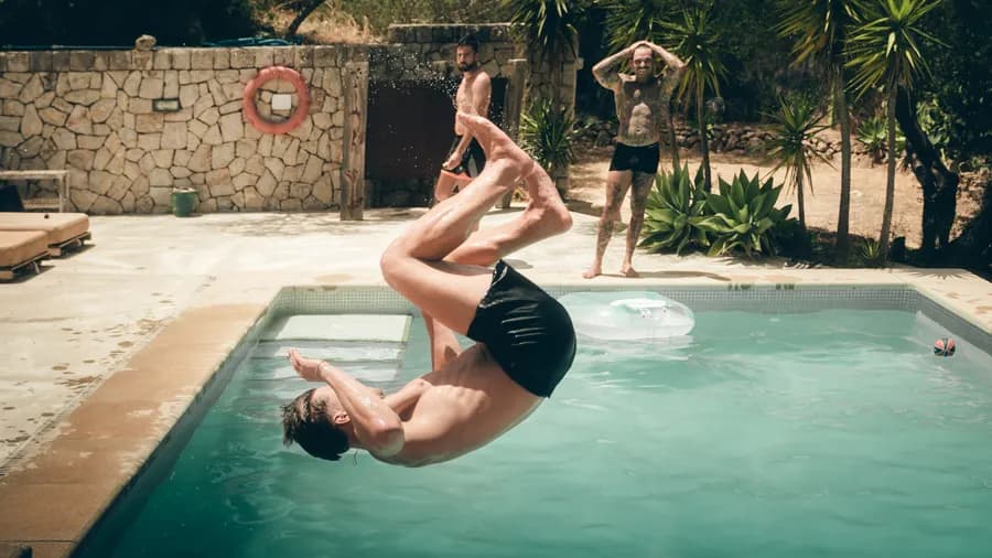 Ein Mann springt mit einem Salto in den Pool.